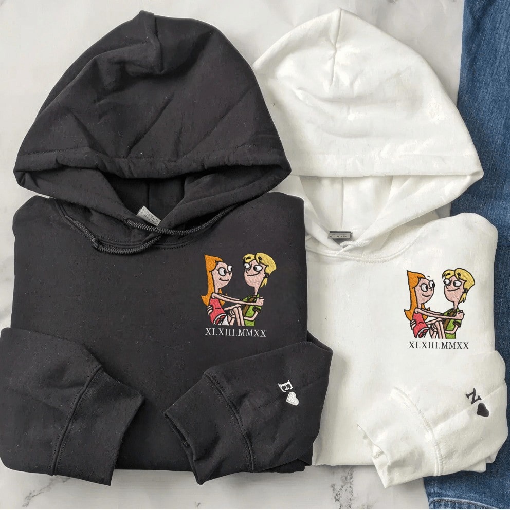 Close-up of matching couple hoodies in pink and black with embroidered heart details.