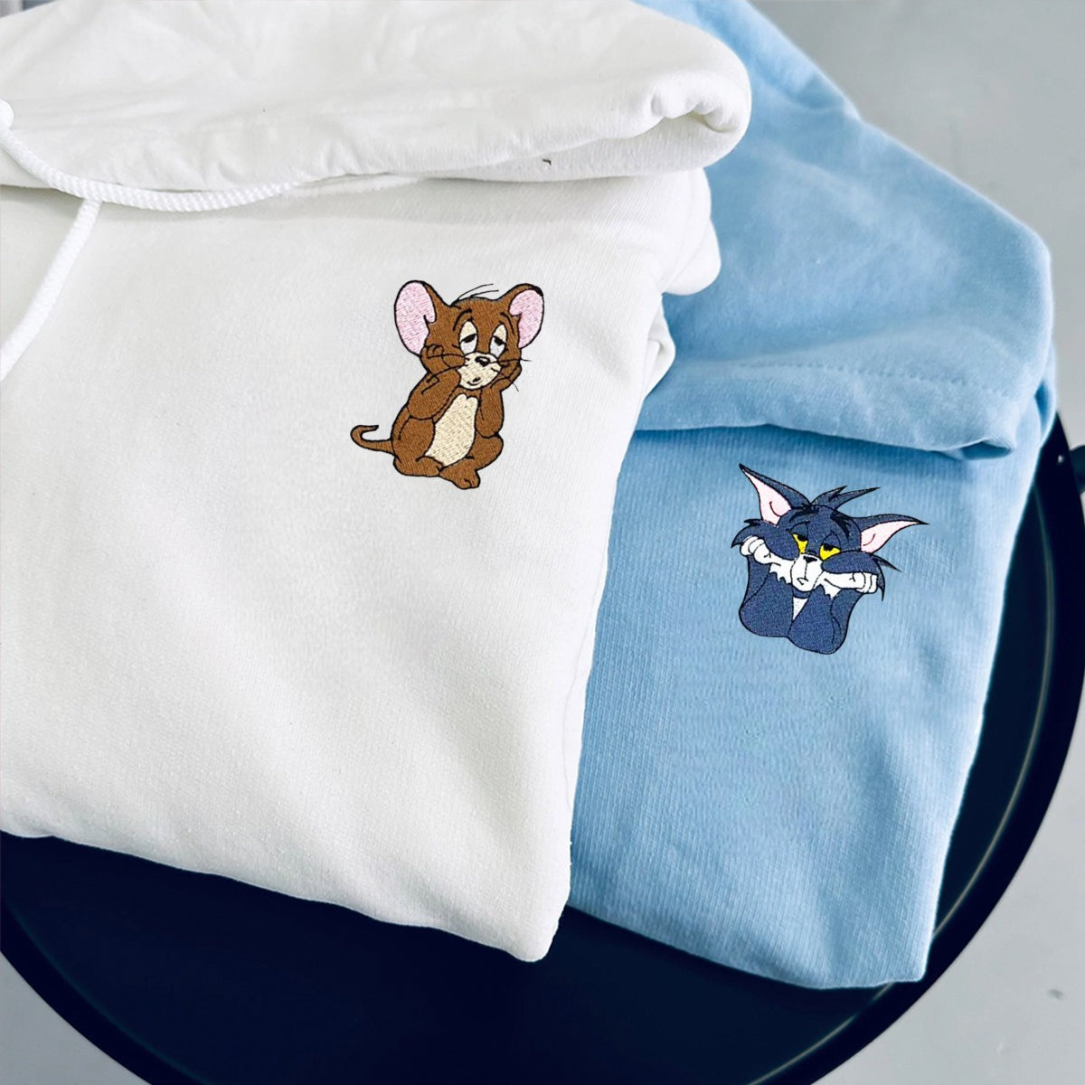White and sky blue hoodies with embroidered mouse and cat designs for couples.