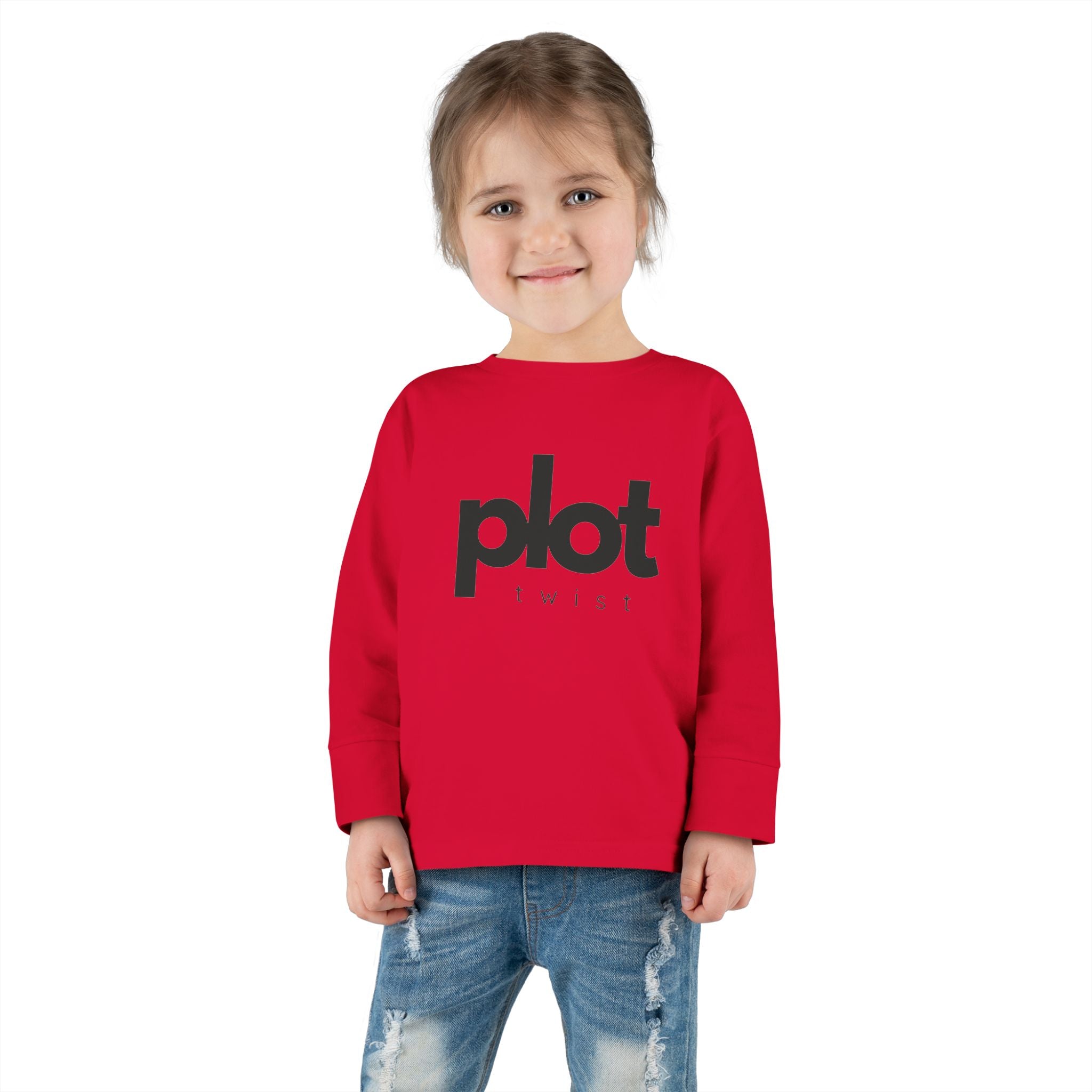 Toddler girl in red Plot Twist tee smiling playfully