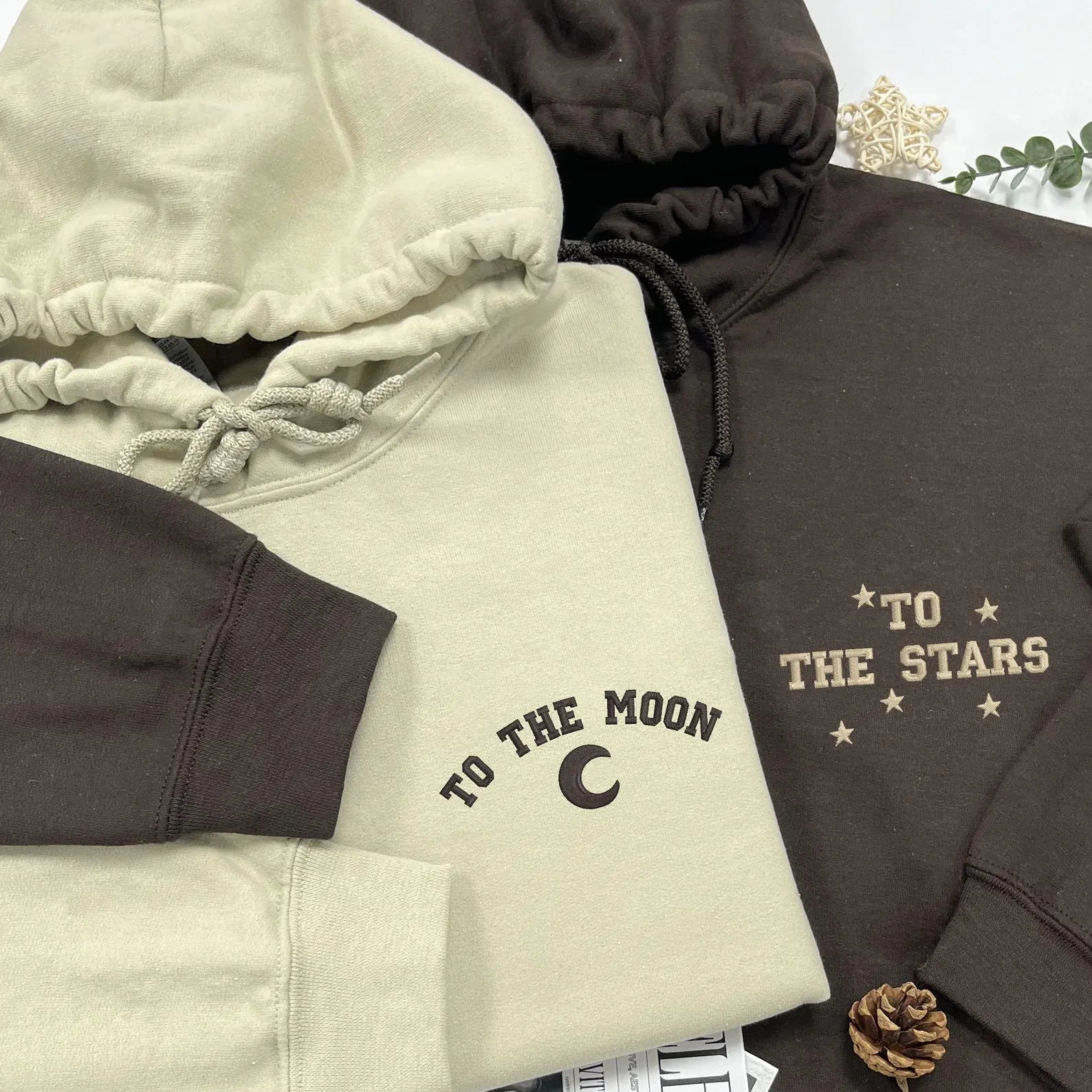 Beige and brown celestial-themed hoodies for couples.