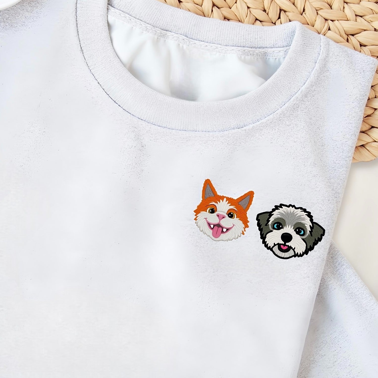 Stack of personalized embroidered sweatshirts featuring dog and cat faces with custom names, in beige, green, and pink colors.

